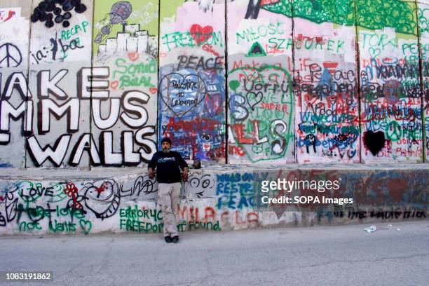 Local Palestinian leaning against the graffiti-covered Separation Wall. The Israeli Separation Wall is a dividing barrier that separates the West...