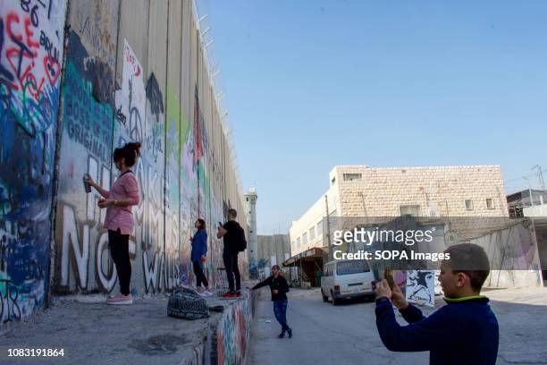 Locals and tourists seen spraying and painting graffiti on the West Bank Separation Wall. The Israeli Separation Wall is a dividing barrier that...