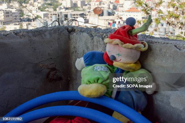 An old toy seen on the balcony of a Palestinian home in the West Bank with the Dheisheh Refugee Camp visible in the background.