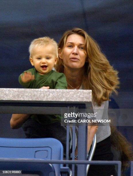 Steffi Graf holds her son Jaden Gil as they watch husband and father Andre Agassi's match against Justin Gimelstob 29 August, 2002 at the US Open in...