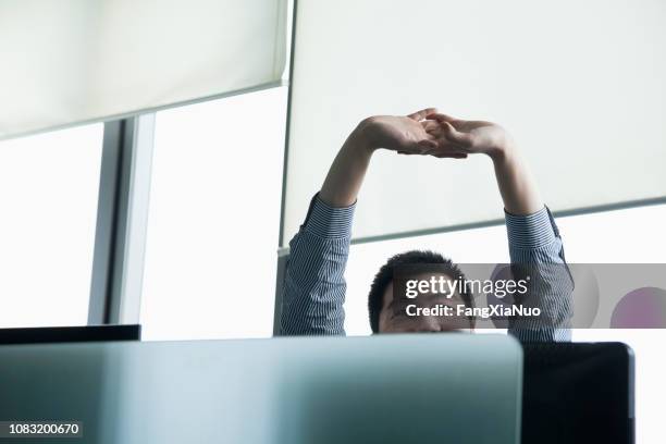 chinese zakenman die zich uitstrekt in office - easy stockfoto's en -beelden