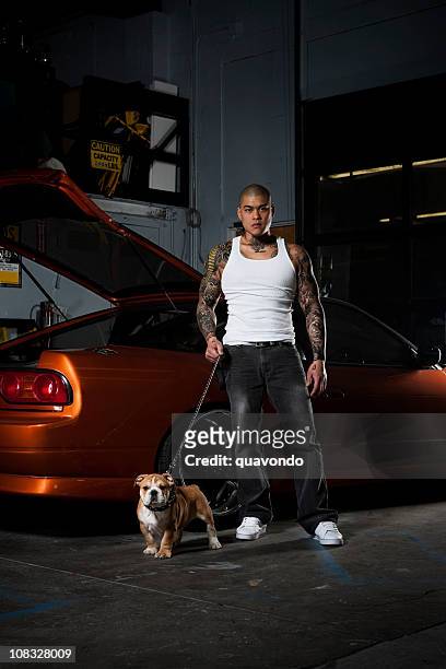 asian male with bulldog, tattoos, and race car, copy space - animal macho stockfoto's en -beelden