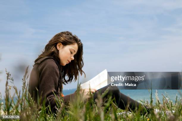 child reading poetry by the sea - poet stock pictures, royalty-free photos & images