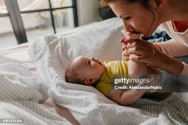 smiling baby und seine mutter - family feet stock-fotos und bilder