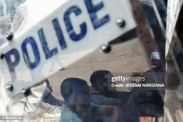 Zimbabwean anti-riot police forces watch men, arrested during violent protests triggered by a sudden rise in fuel prices announced by Zimbabwean...