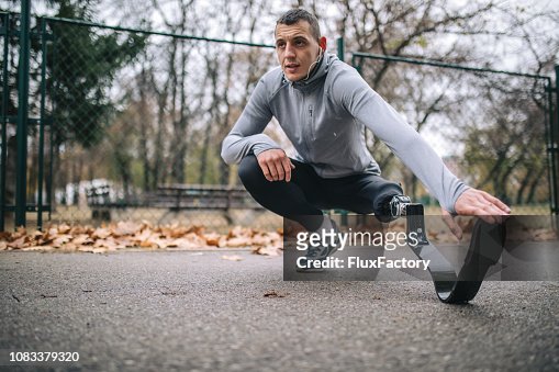 Motivated amputee athlete stretching before running