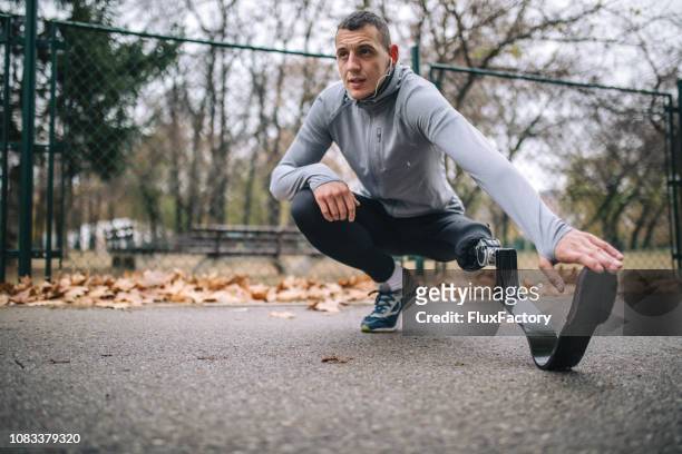 motivated amputee athlete stretching before running - adaptive athlete stock pictures, royalty-free photos & images