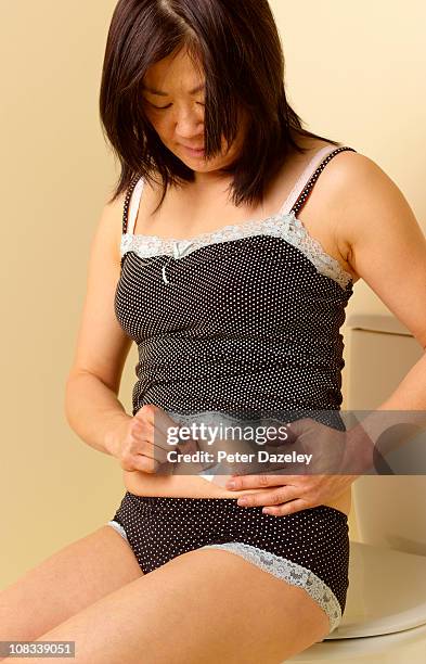 49 year old woman applying hrt patch on stomach - applying bandaid stock pictures, royalty-free photos & images