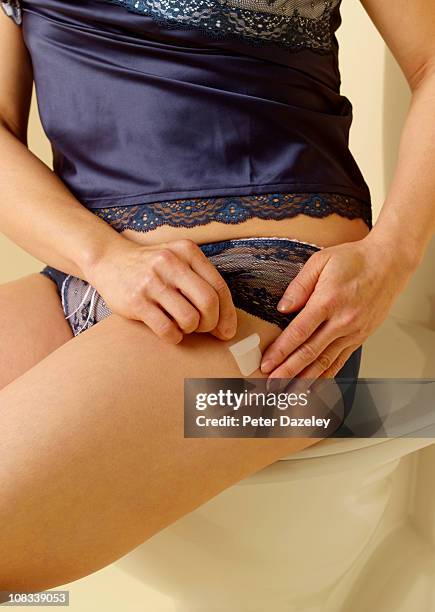 49 year old woman applying hrt patch - hormonas stock pictures, royalty-free photos & images