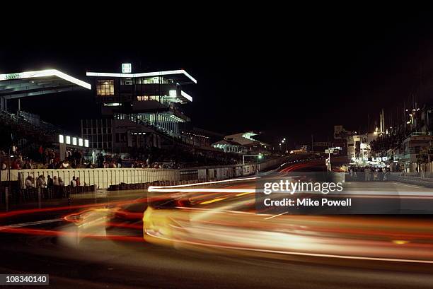 Streaks of tail lights at night along the front straight past the pits and main grandstand during the World Endurance Championship 24 Hours of Le...