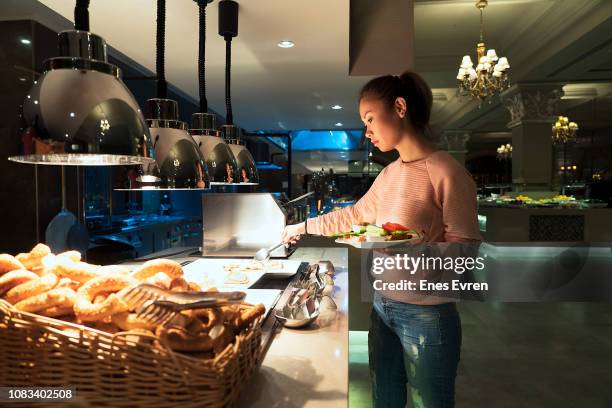 woman helping herself to the breakfast buffet in a luxury hotel's restaurant - breakfast buffet stock pictures, royalty-free photos & images