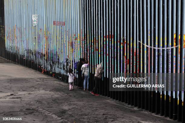 Family of Central American migrants look through the US-Mexico border fence, as seen from Playas de Tijuana, in Baja California state, Mexico, on...