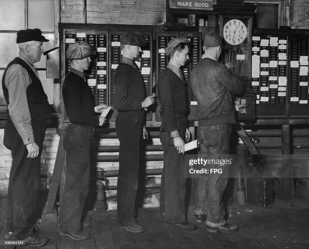 Clocking Off A group of workers waiting in line to clock on at a factory, circa ...