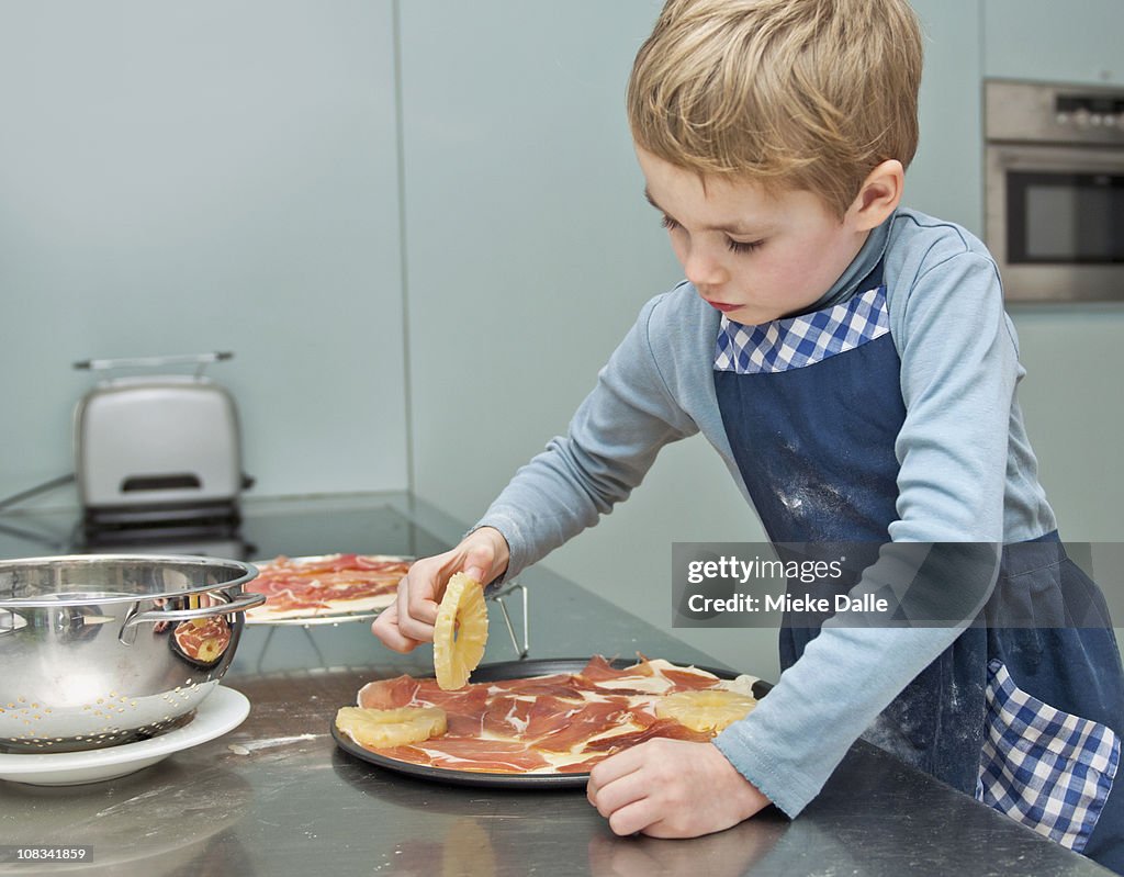 Child making a pizza in kitchen, step-by-step