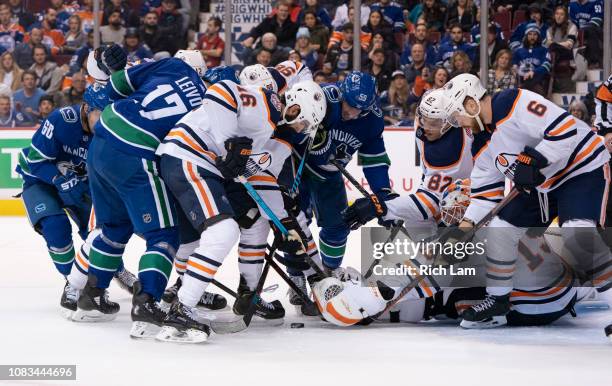 Goalie Mikko Koskinen of the Edmonton Oilers reaches to to try and cover up the puck while Jujhar Khaira, Jesse Puljujarvi, Caleb Jones and Adam...