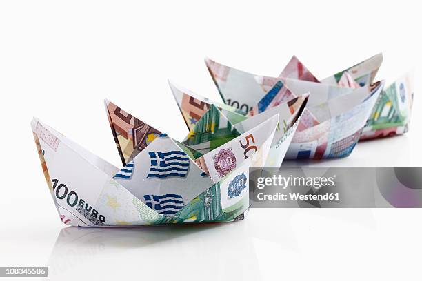 origami paper boats of euro notes on white background - origami boat stock pictures, royalty-free photos & images