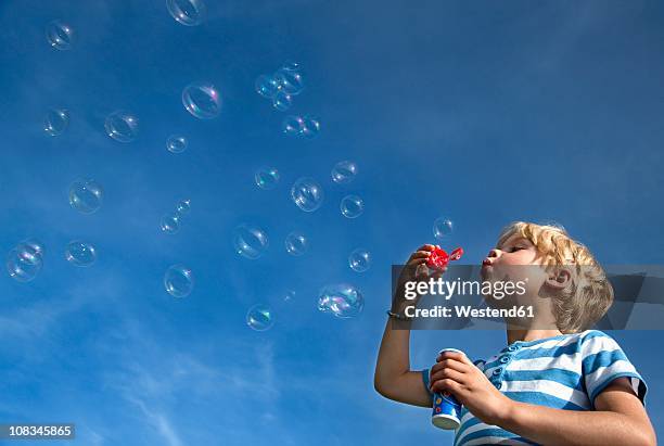 germany, bavaria, boy (4-5 years) blowing soap bubbles - bubble wand photos et images de collection