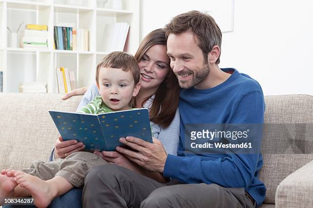 germany, bavaria, munich, parents reading book with son (2-3 years) in living room - 2 3 years stock-fotos und bilder