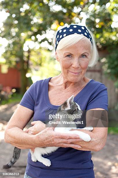 germany, saxony, senior woman pampering a kitten, smiling - old woman cat stock-fotos und bilder