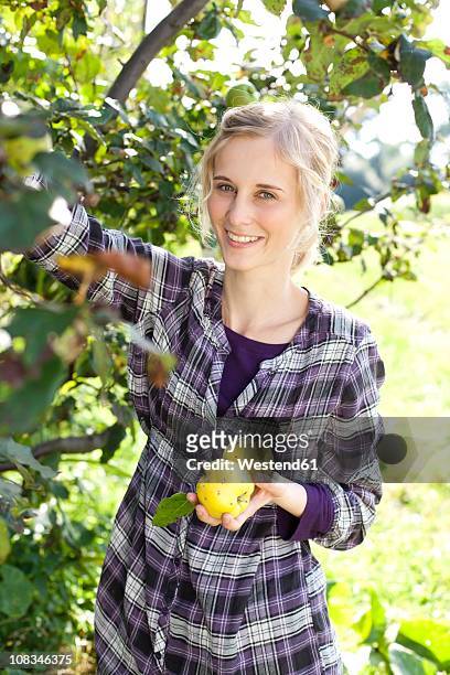 germany, saxony, young woman holding vegetable, smiling, portrait - quince stock pictures, royalty-free photos & images