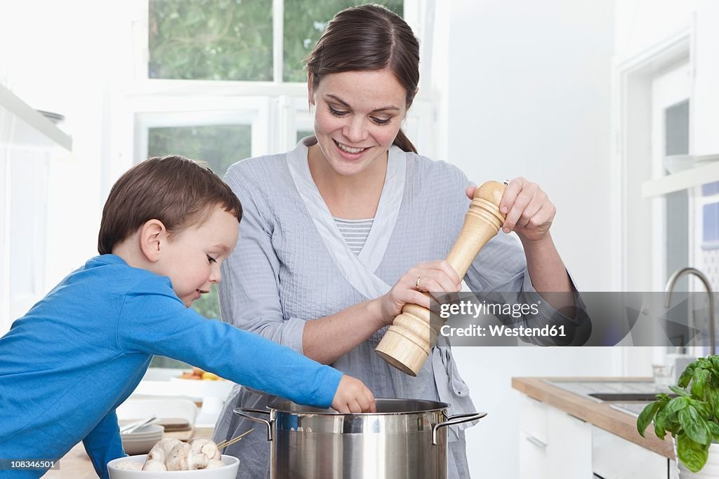 Germany, Bavaria, Munich, Mother and son (2-3 Years) preparing meal in kitchen