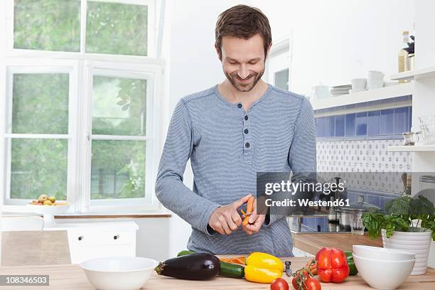 germany, bavaria, munich, man peeling carrot for meal - descascador - fotografias e filmes do acervo