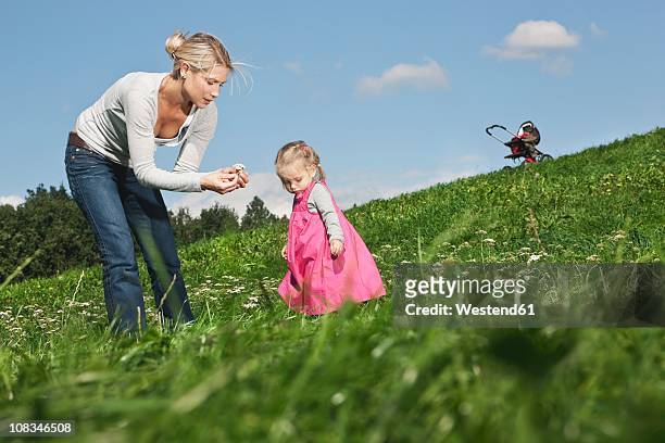germany, cologne, mother showing flower to her daughter (2-3 years) - 30 34 years stock-fotos und bilder