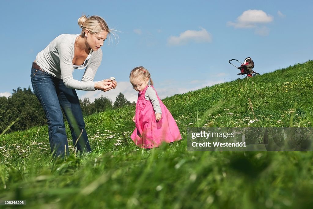 Germany, Cologne, Mother showing flower to her daughter (2-3 Years)