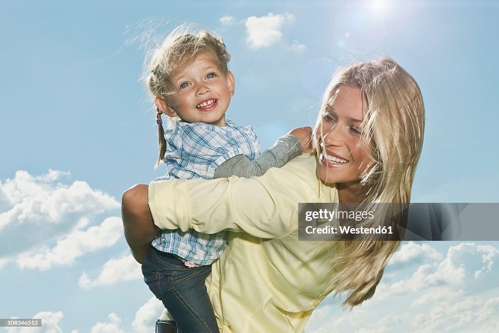 Germany, Cologne, Mother carrying her daughter (2-3 Years) on back