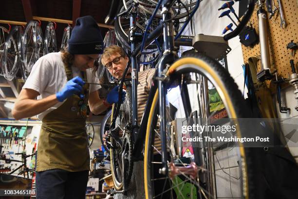 Oak City Cycling Project's mechanic Charles Thompson, center, helps regular customer Bryan Hoffman, work on his bike at the underground garage space...
