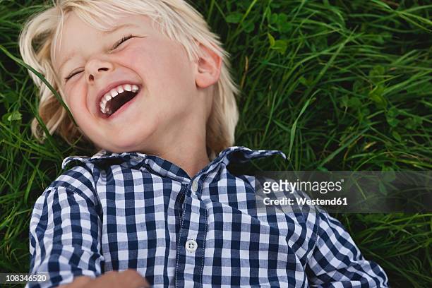 germany, cologne, boy (2-3 years) lying on grass and laughing - 2 3 years stock-fotos und bilder