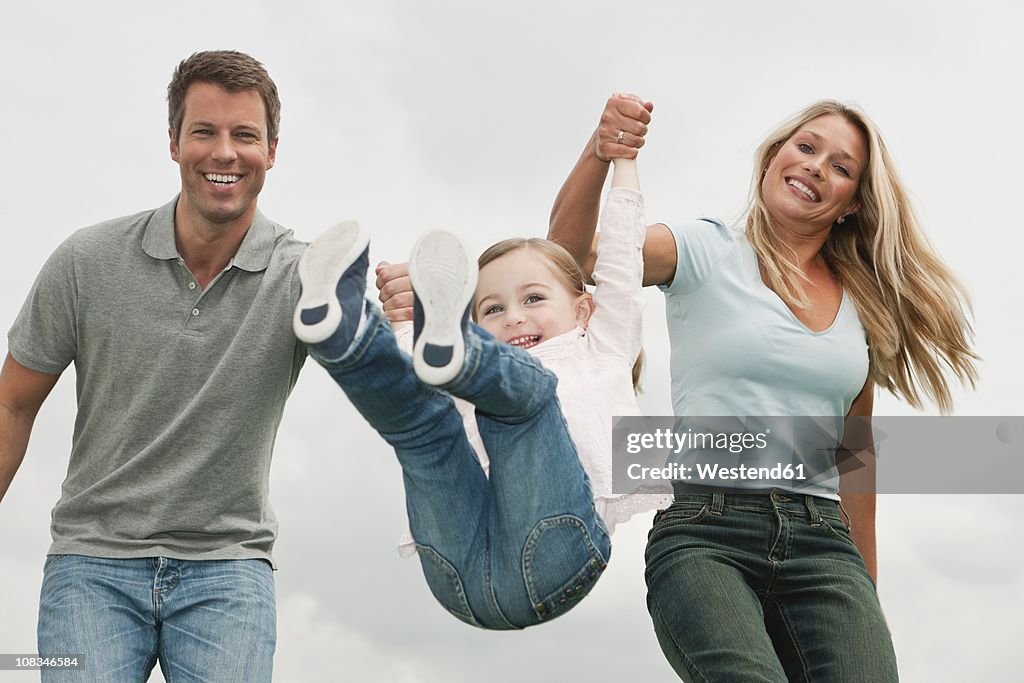 Germany, Cologne, Parents swings her daughter (2-3 Years), smiling