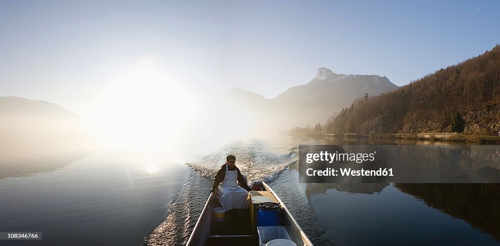 Austria, Mondsee, View of fisherman in boat near lake