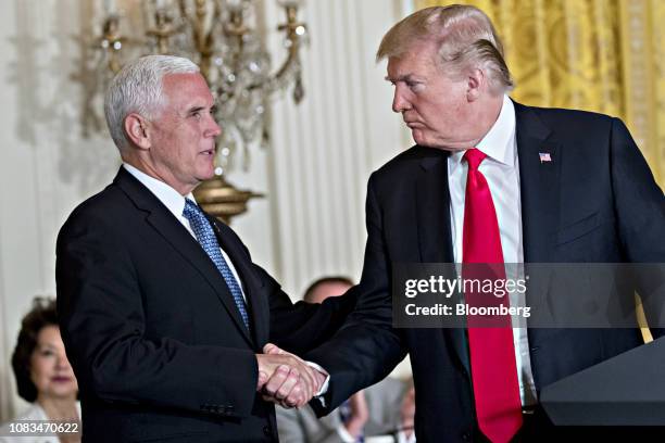 President Donald Trump, right, shakes hands with U.S. Vice President Mike Pence during a National Space Council meeting in the East Room of the White...