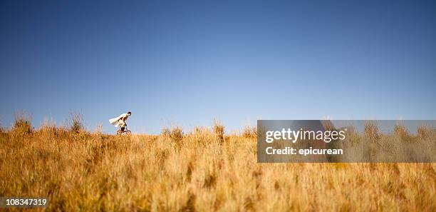 man riding miniature bike wearing a cape - extreem weer stock pictures, royalty-free photos & images