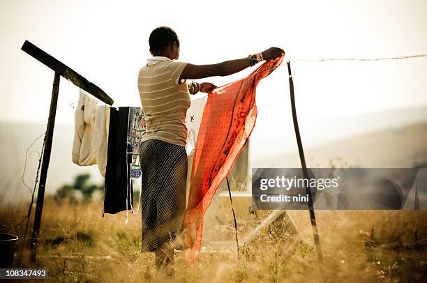 woman hanging laundry in rural africa - laundry africa stock pictures, royalty-free photos & images