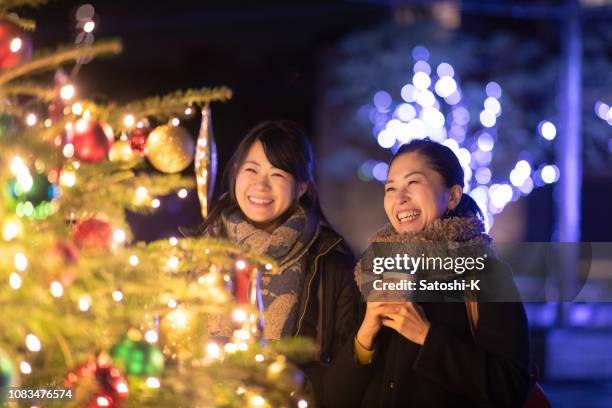 happy female friends enjoying christmas lights - minato stock pictures, royalty-free photos & images