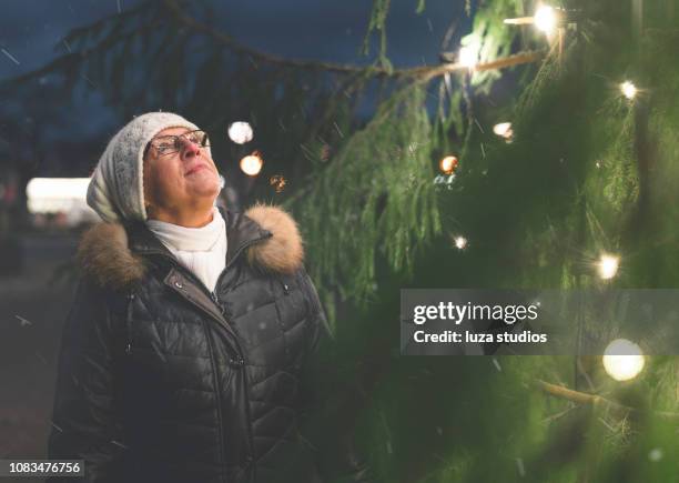 senior woman looking at a christmas tree in sweden - winter tradition stock pictures, royalty-free photos & images