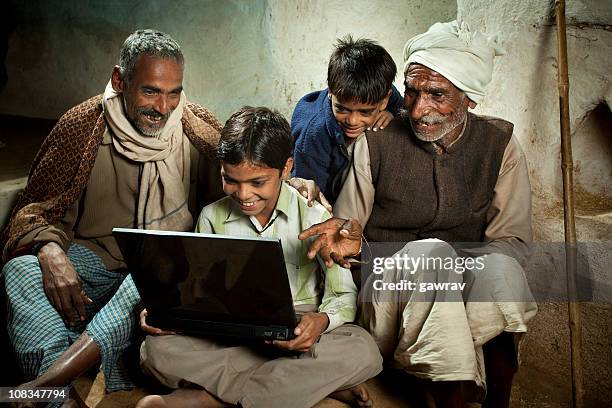 village boy with father, grandfather and brother using a laptop - rural internet stock pictures, royalty-free photos & images