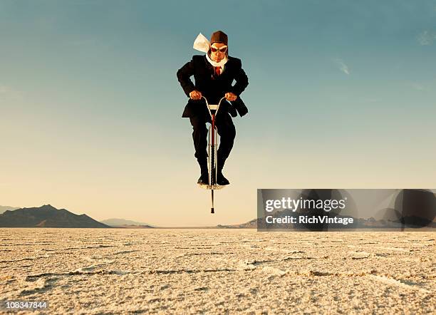 businessman on pogo stick in desert - man bending forward stock pictures, royalty-free photos & images