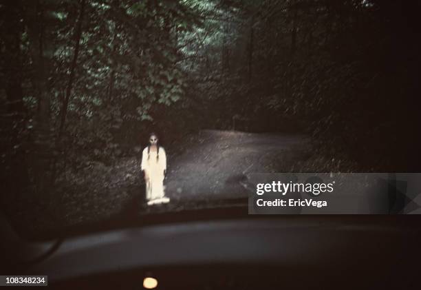 spooky ghost in white standing in the middle of a dark road - soul stories stock pictures, royalty-free photos & images