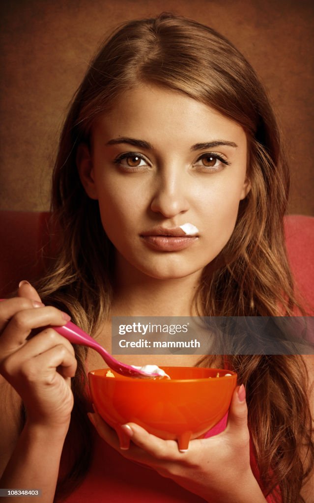 Chica comiendo yogur con corn flakes (Copos de maíz)