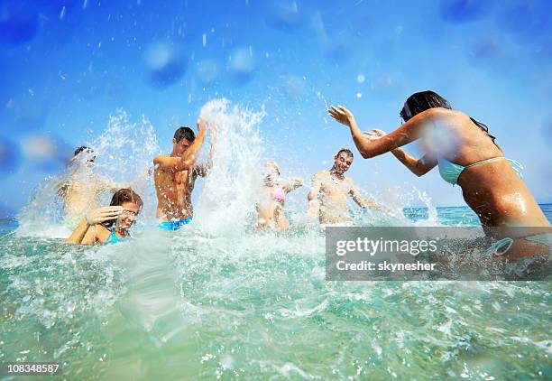 junge menschen im wasser sprühen jeder andere. - hüfttief im wasser stock-fotos und bilder