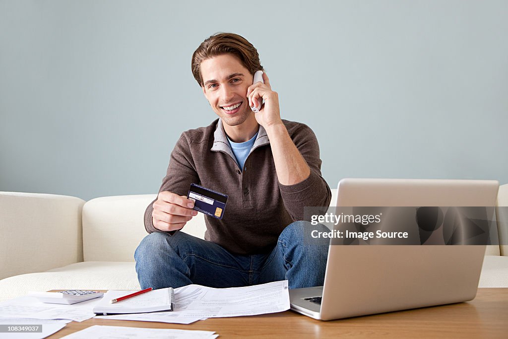 Young man with credit card using laptop