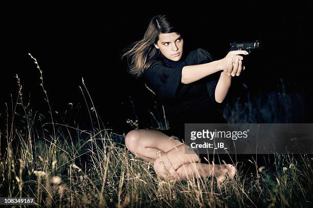 young beautiful girl aiming a gun - female gangster stock pictures, royalty-free photos & images