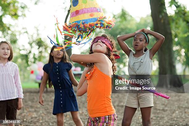 girl at birthday party hitting pinata - pineta stock-fotos und bilder
