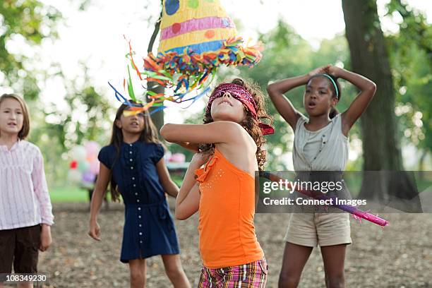 girl at birthday party hitting pinata - pinhata imagens e fotografias de stock