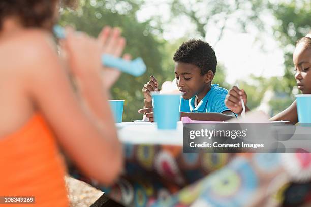 children sitting at picnic table at birthday party - picnic table park stock pictures, royalty-free photos & images