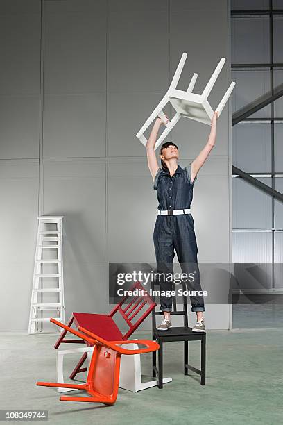 young woman lifting chair above her head - ladder chair stock pictures, royalty-free photos & images