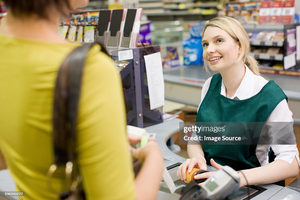 Female cashier and customer at supermarket checkout